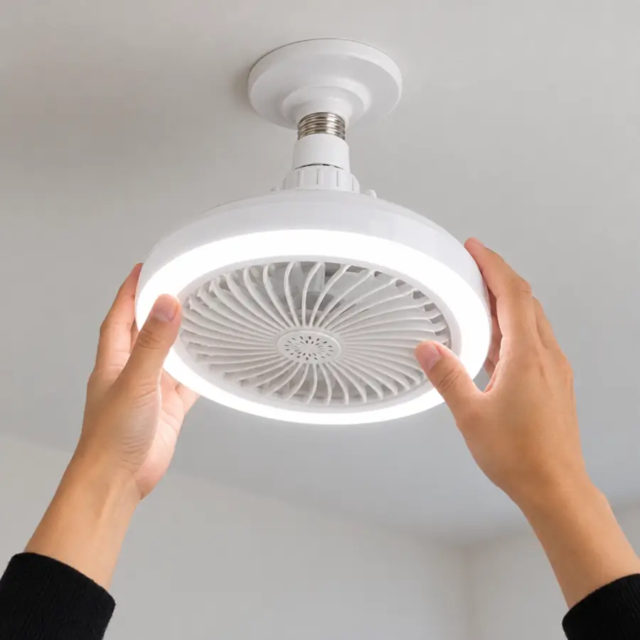 Manos enroscando el foco-ventilador en el soquete del techo